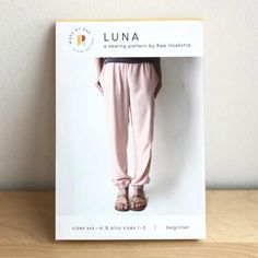 an image of a woman's legs in pink pants and sandals on a wooden table