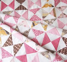 a close up of a quilt made with pink and brown triangles on white fabric,