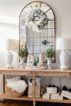 a console table with christmas decorations on it and a mirror in the corner behind it