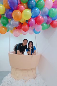 two people sitting in a large balloon filled with balloons