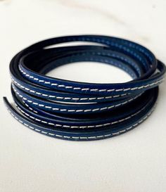 the blue leather cord has white stitching on it and is lined up in rows