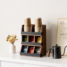 a coffee cup holder on top of a white table next to a sign and some cups