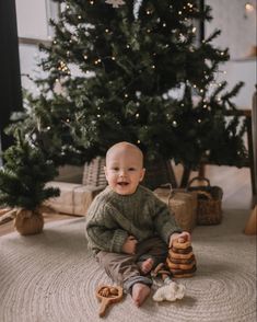 a baby sitting in front of a christmas tree