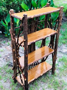 a wooden shelf made out of sticks and branches in the grass with plants behind it