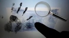 a hand and fingerprints under a magnifying glass with a person's hand