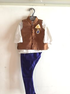 The nehru sleeveless jacket or vest is so on trend now. This is a classic combination of tan raw silk vest, a white silk brocade kurta and navy jodhpur pants.  Dress is custom made. Once you order I'll send you a measurements sheet which you need to fill out with your child's measurements. Alternately, you could just choose an age group in which case I would use the standard measurements for that age. Please allow 1-2 weeks for the order to get processed and shipped as the dress is made with love just for you! Shipping takes 4-5 days. We use FedEx with tracking number and on call support. Kids Designer Outfits, Brocade Kurta, Gold Sequin Blouse, Jodhpur Pants, Silk Vest, Nehru Jacket, Kids Couture, Designer Outfits, Nehru Jackets