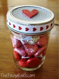 a jar filled with candy hearts on top of a wooden table