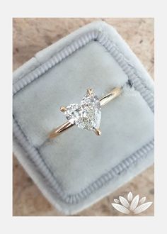 an engagement ring with a pear shaped diamond in it on a velvet box that is sitting on a marble surface