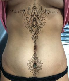 a woman's stomach with an intricate tattoo on it