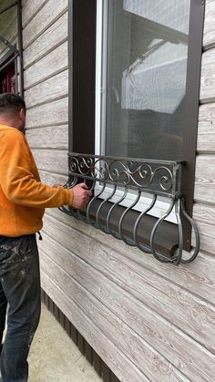 a man in an orange jacket is opening the window