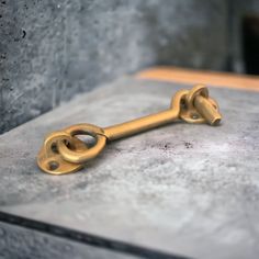 an old key is sitting on top of a cement surface in front of a stone wall