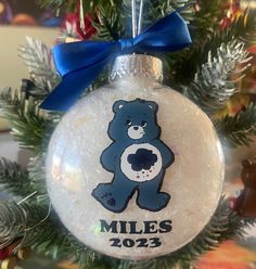 a glass ornament with a teddy bear on it's side and the name miles