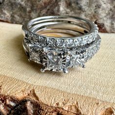 three diamond wedding rings sitting on top of a piece of wood next to each other