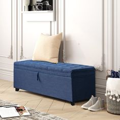 a blue storage bench sitting on top of a hard wood floor next to a white wall