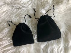 two black velvet bags sitting on top of a white fur covered floor next to each other