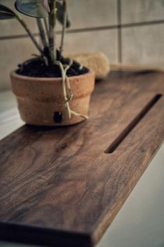 a potted plant sitting on top of a wooden cutting board next to a tile wall