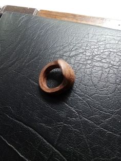 a wooden ring sitting on top of a black leather table cloth covered surface with white background