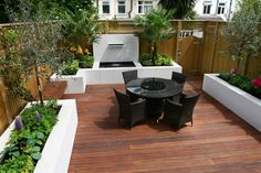 an outdoor patio with wooden decking and potted plants