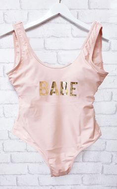 a bathing suit with the word babe on it hanging up against a brick wall in front of a white brick wall