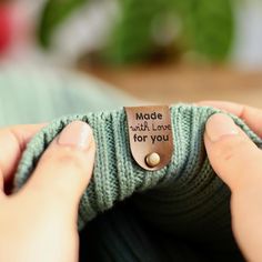 a person holding a green sweater with a tag that says made with love for you