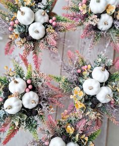 two wreaths with white flowers and greenery on them