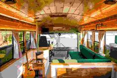 the inside of a bus with green couches and tables in front of windows on both sides