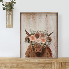 a cow with flowers on its head is shown in front of a wooden wall and vase