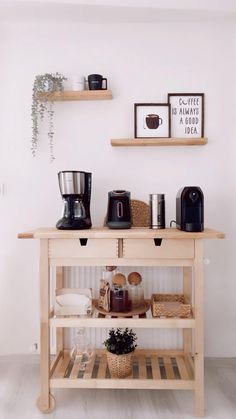 a wooden shelf with coffee cups and other items on it in front of a white wall