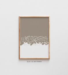 an art piece hanging on the wall in front of a white wall with arabic writing