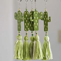 green cactus keychains hanging from hooks with tassels in the shape of cacti