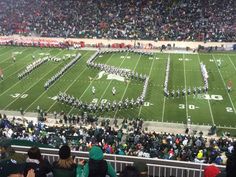 a football stadium filled with lots of people and marching band members on the field during a game