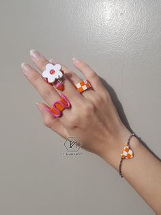 a woman's hand with two rings on it and an orange and white flower