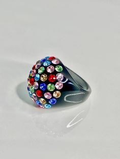 This glamorous ring is handcrafted on a black acrylic dome shaped setting, while embellished with multicolored mixed Swarovski crystal stones. The ring is lightweight, comfortable to wear, and is perfect for styling up with any look. The care and craftsmanship that went into creating this ring truly showcases itself as art at your fingertips. The ring sparkles even more beautifully in person and you will get endless complements when wearing this ring. Arrives beautifully packaged in a luxury gif Multicolor Crystal Rings For Party, Unique Multicolor Rings For Party, Multicolor Enamel Ring, Multicolor Crystal Rings For Gift, Multicolor Multi-stone Rings For Parties, Multicolor Party Ring Jewelry, Multicolor Multi-stone Party Rings, Rainbow Ring For Party Jewelry, Party Crystal Ring With Rhinestones