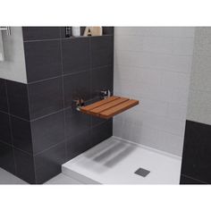 a small wooden shelf in the corner of a shower stall with tiled walls and floor