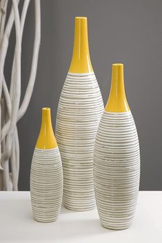 three yellow and white vases sitting next to each other