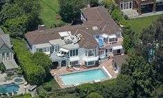 an aerial view of a large house with a swimming pool in the foreground and a woman's face