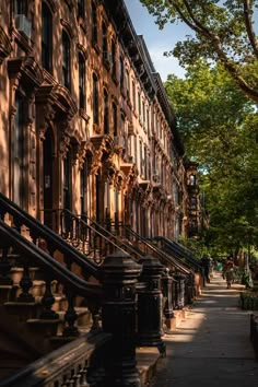 an old building with many windows and balconies on the outside, next to a tree lined sidewalk