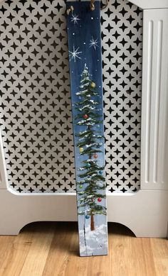 a snowboard with a christmas tree painted on it sitting in front of a wall