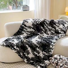 a black and white crocheted blanket sitting on top of a couch next to a window