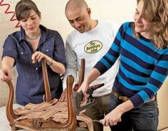 three people are working on an old fashioned chair with wood and leather trimmings