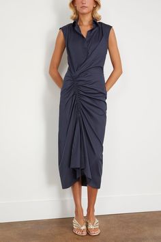 The Callas Milano Sylvie is a sleeveless shirt dress with a gathered front creating a ruched sarong design. A classic point collar and button placket front is featured at the top of the dress, while the gathering over the right leg makes a contrast to the tailored look. The dress is midi-length. Made from a light weight Italian stretch cotton poplin. FIT DESCRIPTION 69% Cotton, 25% Polyamide, 6% Elastane Sleeveless, collared, gathered dress Midi length Professional dry cleaning recommended Harri Summer Formal Dresses With Gathered Waist, Summer Workwear Dresses With Gathered Skirt, Ruched Midi Length Sleeveless Dress For Work, Ruched Sleeveless Midi Dress For Work, Formal Sleeveless Dress With Gathered Skirt, Ruched Draped Dress For Workwear, Ruched Draped Dress For Work, Sleeveless Midi Dress With Gathered Skirt For Daywear, Elegant Gathered Skirt Dresses For Daywear