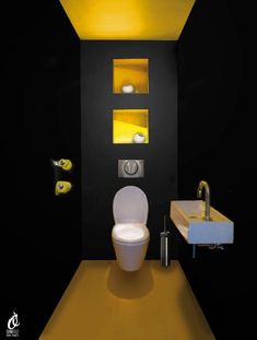 a modern bathroom with black walls and yellow lighting on the ceiling, along with a white toilet