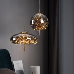 two lights hanging from the ceiling above a bed in a room with grey walls and curtains