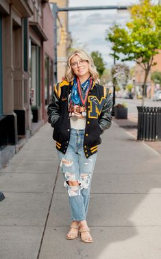 a woman standing on the sidewalk in ripped jeans