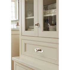 a white cabinet with glass doors and drawers