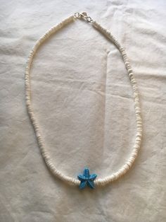 "A white shell necklaces with a blue glass starfish charm.  The necklace is 18\" in length.  The price includes priority shipping with insurance." White Star-shaped Jewelry With Starfish Charm, Beach Star Charm Necklace, Turquoise Necklace With Starfish Charm For Beach, Turquoise Necklaces With Starfish Charm For Beach, Beach Turquoise Necklace With Starfish Charm, Ocean-inspired Starfish Beaded Necklaces, White Star-shaped Ocean-inspired Jewelry, Ocean-inspired White Star-shaped Jewelry, Ocean-inspired White Star Jewelry