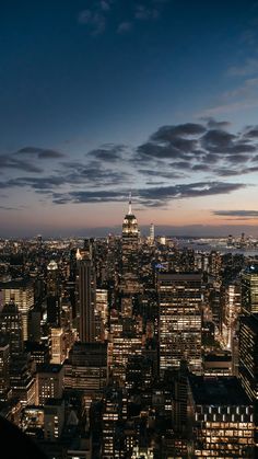 the city skyline is lit up at night, with skyscrapers in the foreground