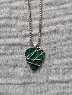 a green heart shaped pendant on a chain