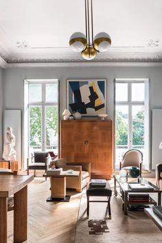 a living room filled with lots of furniture next to large windows on the wall and wooden flooring