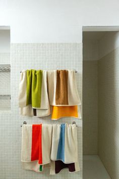 towels hanging on hooks in a bathroom with white tile walls and flooring below them